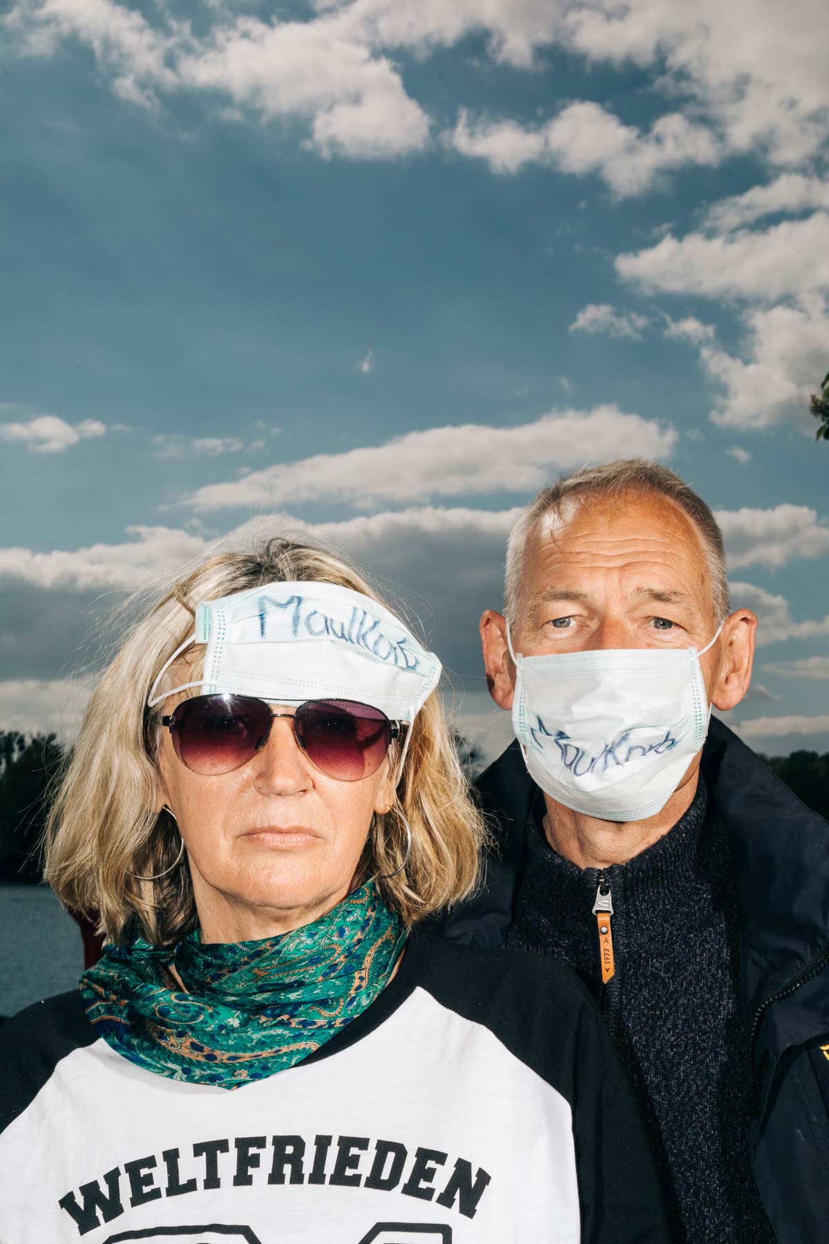 Ilona W. and her husband Andreas pose for a Portrait while demonstrating at a „hygiene demo“ in Hanover together with right-wing extremist conspiracy believers against the measures to limit the spread of corona. Their protective masks read „muzzle“.